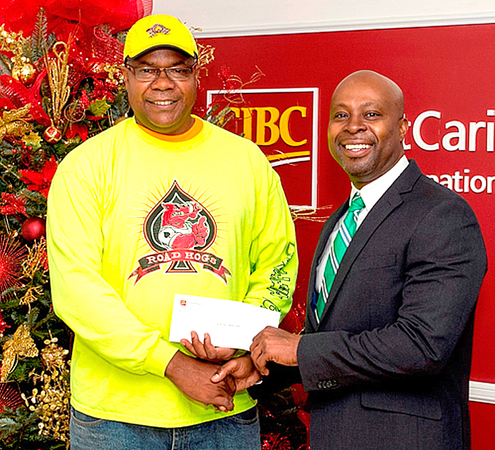 Sean Blyden CIBC FirstCaribbean Shirley Street Branch Manager presents a donation to Brian Adderley of Valley Boys, who were the winners of the Boxing Day Parade. 