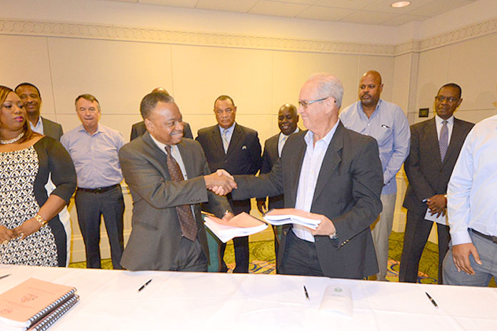 Contract signed to refurbish the Paradise Island East Bridge. Shaking hands are Bridge Authority Chairman Rory Higgs, centre left, and Island Site Development President Larry Treco, centre right. At left, Melissa Hall; at right Naveen Gupta, Chief Operations Officer of Island Site Development. And behind, from left: Stuart Bowe, Paul Burke, Prime Minister Christie, Deputy Prime Minister Davis, Ed Fields and Vincent Peet. (BIS Photo/Peter Ramsay)