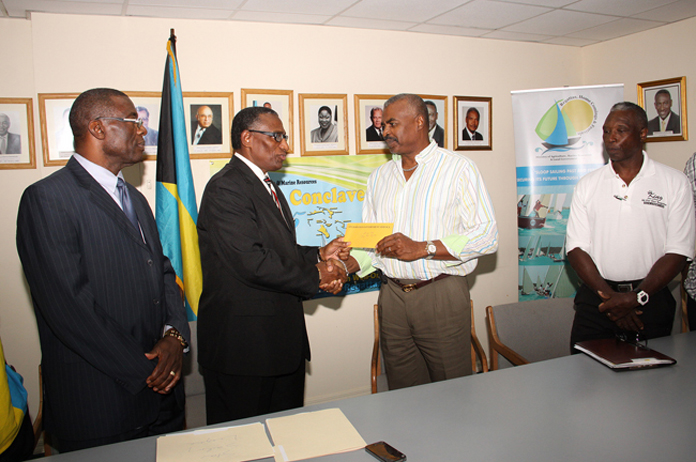 Minister of Agriculture and Marine Resources the Hon. V. Alfred Gray, second left, makes cheque presentation to organizer of the “King Eric” Gibson All For One Regatta -- Eric Gibson, Jr., January 4, 2016 at the Ministry of Agriculture and Marine Resources. 