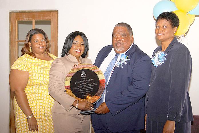 Retiring educator Paul Turnquest accepts a plaque from Mrs. Shenique Mackey-Paul, principal of the United Estates Primary School in San Salvador. He is flanked by Deborah Claridge and his wife Jacintha. (BIS Photo/Patrick Hanna)