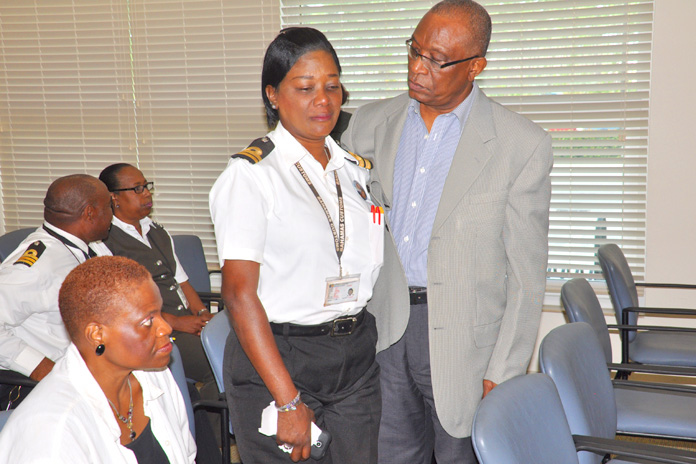 GRIEVING – Assistant Comptroller of Customs, Mr. Skerick Martin assists a grieving Elsa Neely. She was one of many officers, male and female, crying openly Friday as Mr. Martin spoke on the passing of Mr. Kevin Hanna who was reportedly shot by bandits at his South Bahamian home on Thursday afternoon. Also pictured seated is trained psychologist Dr. Pamela Mills.  (BIS Photo/Vandyke Hepburn)