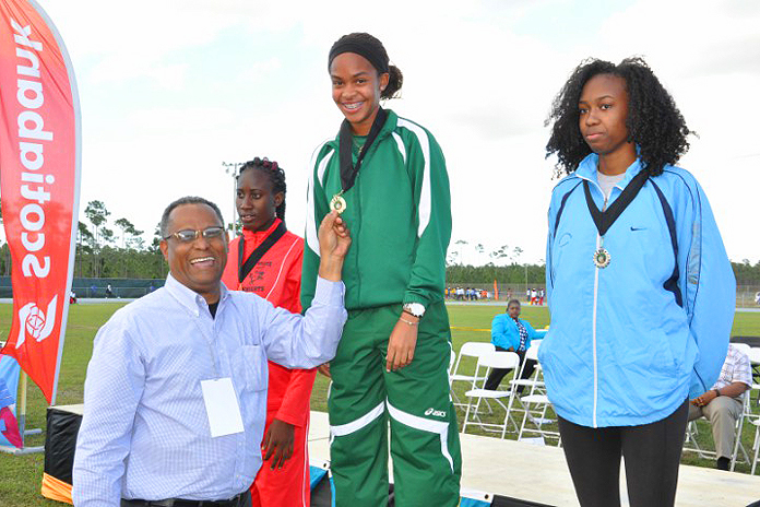 Minister Michael Darville presenting gold to youths at the High School Nationals on Grand Bahama.