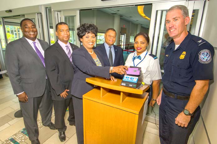 Airport CEO and partners launch the Electronic Boarding Pass system at Lynden Pindling International Airport (LPIA).  From left to right: Kevin McDonald, Vice President, Maintenance and Engineering, Nassau Airport Development Company Ltd. (NAD); Owen McKinney, Supervisor, Airport Authority; Vernice Walkine, President & CEO, NAD scanning her mobile device; Alan Sweeting, Chairman, Airline Operators Committee, LPIA; Alinka Rolle, Security Screener, Airport Authority; and Jeffrey Mara, Port Director, United States Customs and Border Protection.