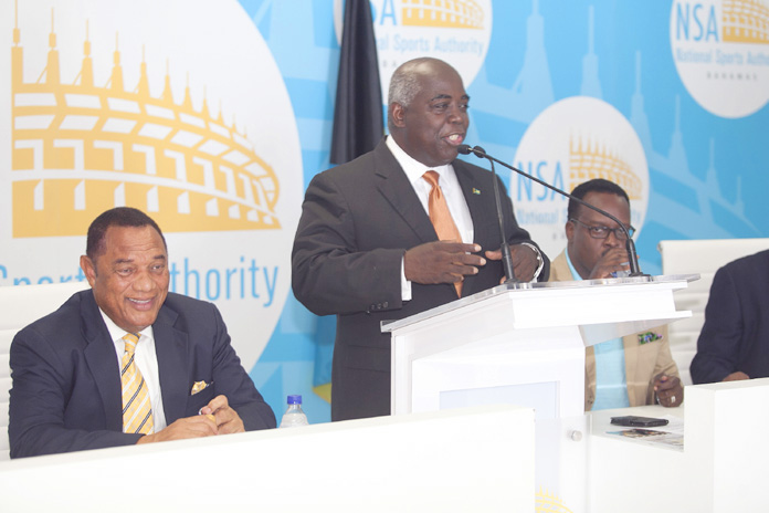 Minister of Works and Urban Development the Hon. Philip Davis, at podium, presents the plans for the Andre Rodgers National Baseball Stadium at the $21 million contract signing, July 18, 2016 at the Thomas A. Robinson National Stadium. Prime Minister and Minister of Finance the Rt. Hon. Perry Christie is at left; Minister of Youth, Sports and Culture the Hon. Dr. Daniel Johnson, at second right; and Permanent Secretary Calvin Balfour, at right. (BIS Photo/Derek Smith) 