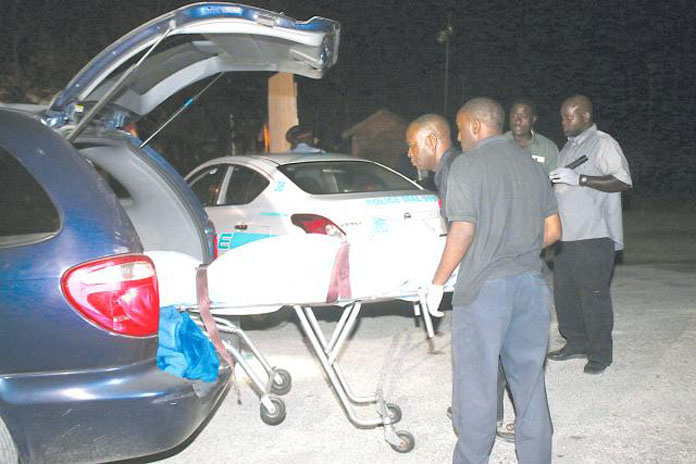 Morticians take away the body of a young girl caught in the gunfire of a gang shootout at the Sand Trap Bar on West Bays Street last evening. Photo by Nassau Guardian. 