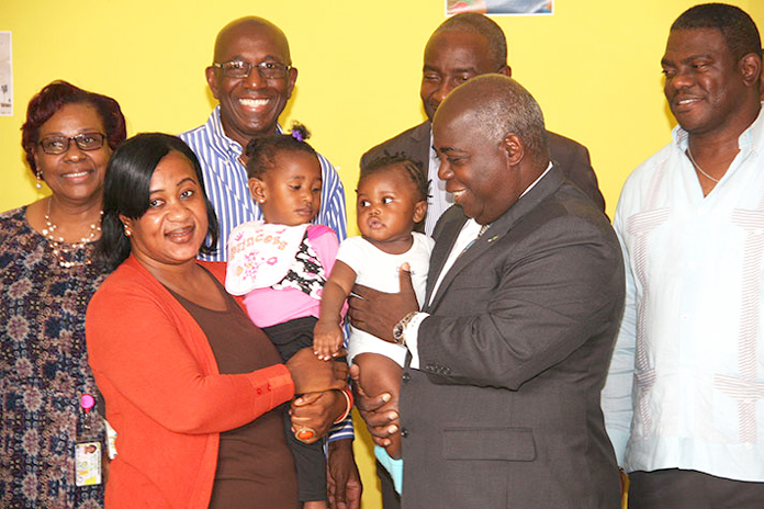 Deputy Prime Minister and Minister of Works and Urban Development the Hon. Philip Davis is pictured with the two toddlers presently enrolled in the Downtown Straw Market's new Day Care Centre. Also shown are representatives of the Straw Market Authority, including Chairman Kevin Simmons, third left. (BIS Photo/Patrick Hanna)